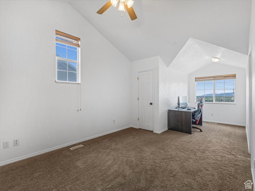 Unfurnished office with lofted ceiling, a ceiling fan, carpet, and baseboards