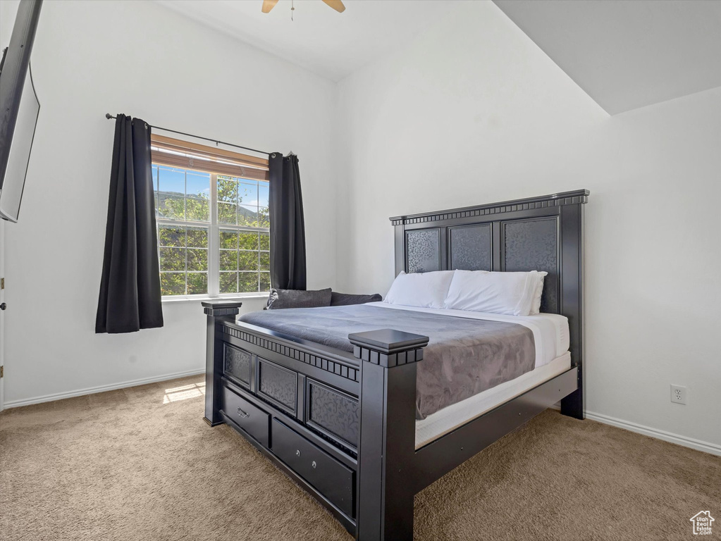 Carpeted bedroom featuring baseboards, ceiling fan, and lofted ceiling
