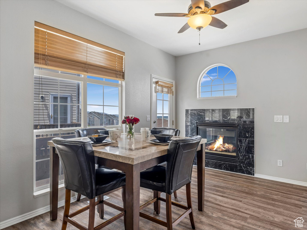 Dining space with wood finished floors, a high end fireplace, baseboards, and ceiling fan