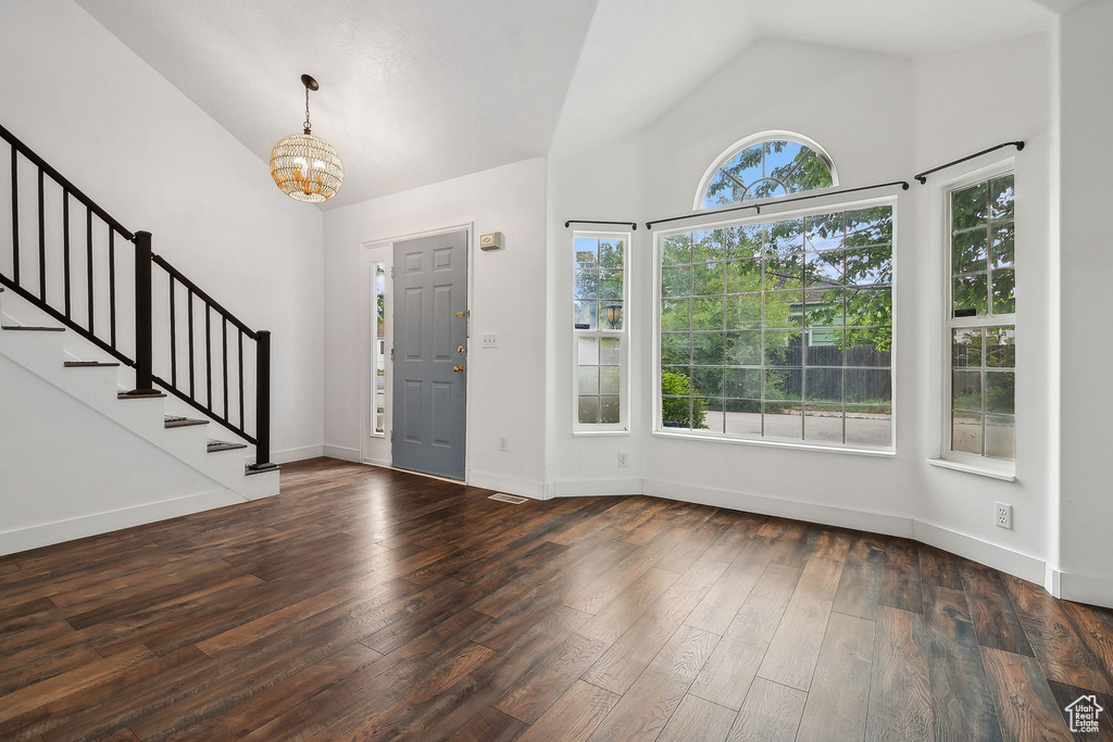 Entryway featuring a chandelier, stairs, hardwood / wood-style flooring, high vaulted ceiling, and baseboards