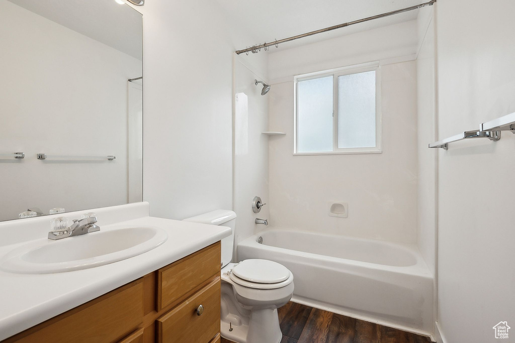 Full bathroom with toilet, shower / bath combination, vanity, and wood finished floors