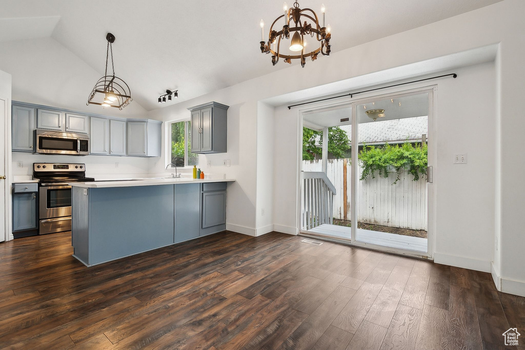 Kitchen with appliances with stainless steel finishes, gray cabinets, a sink, dark wood-style flooring, and vaulted ceiling