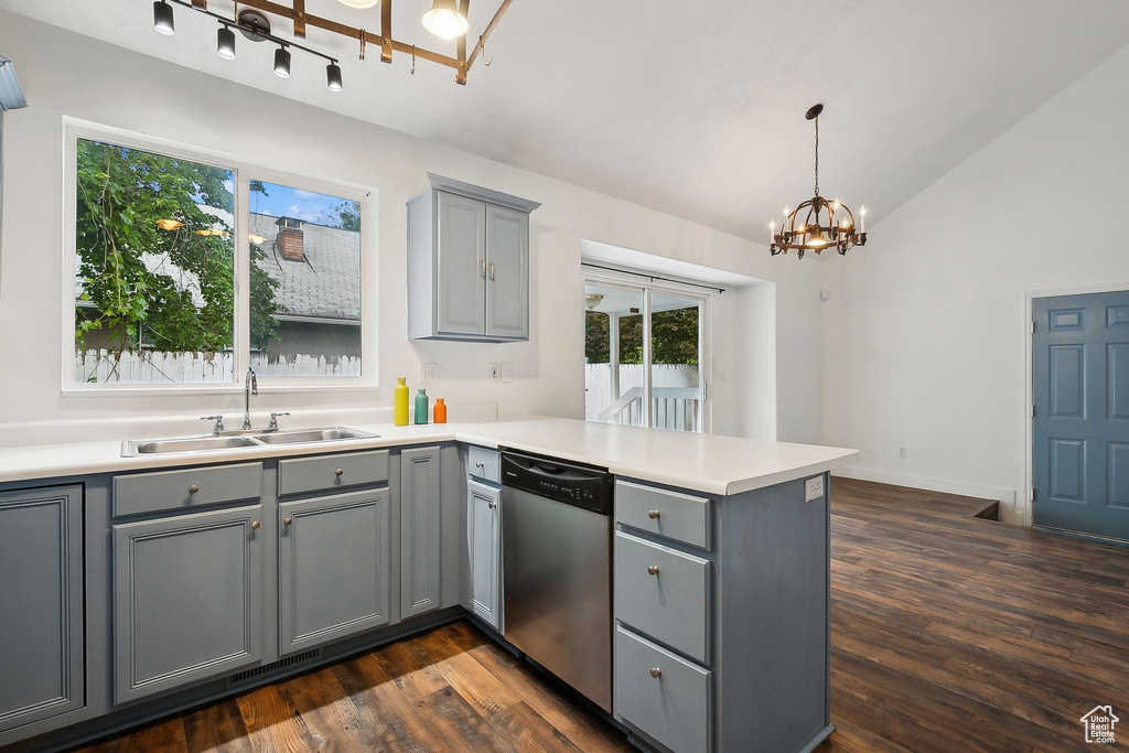 Kitchen featuring stainless steel dishwasher, gray cabinets, a sink, a peninsula, and a chandelier