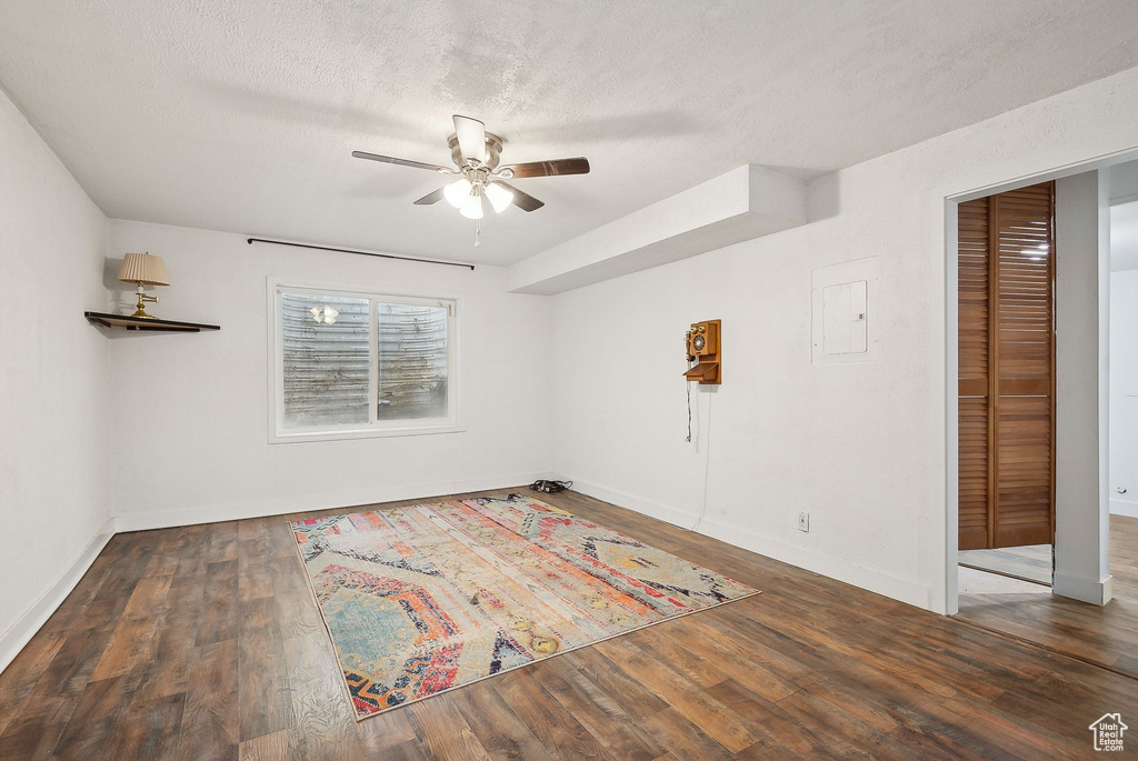Empty room featuring ceiling fan, wood finished floors, baseboards, and a textured ceiling