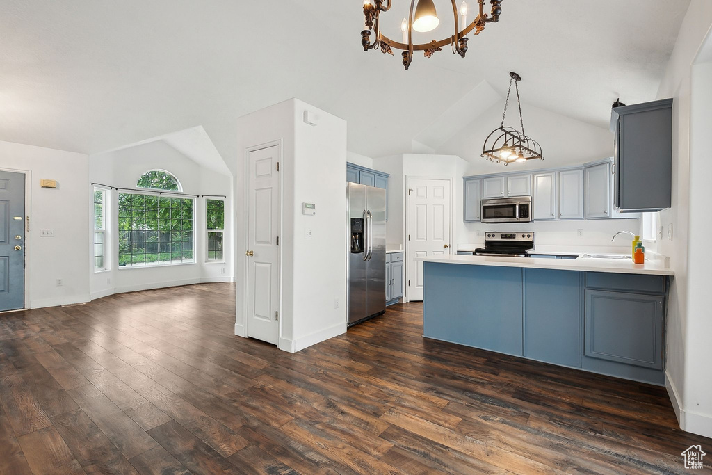 Kitchen featuring appliances with stainless steel finishes, a sink, a peninsula, a chandelier, and gray cabinetry