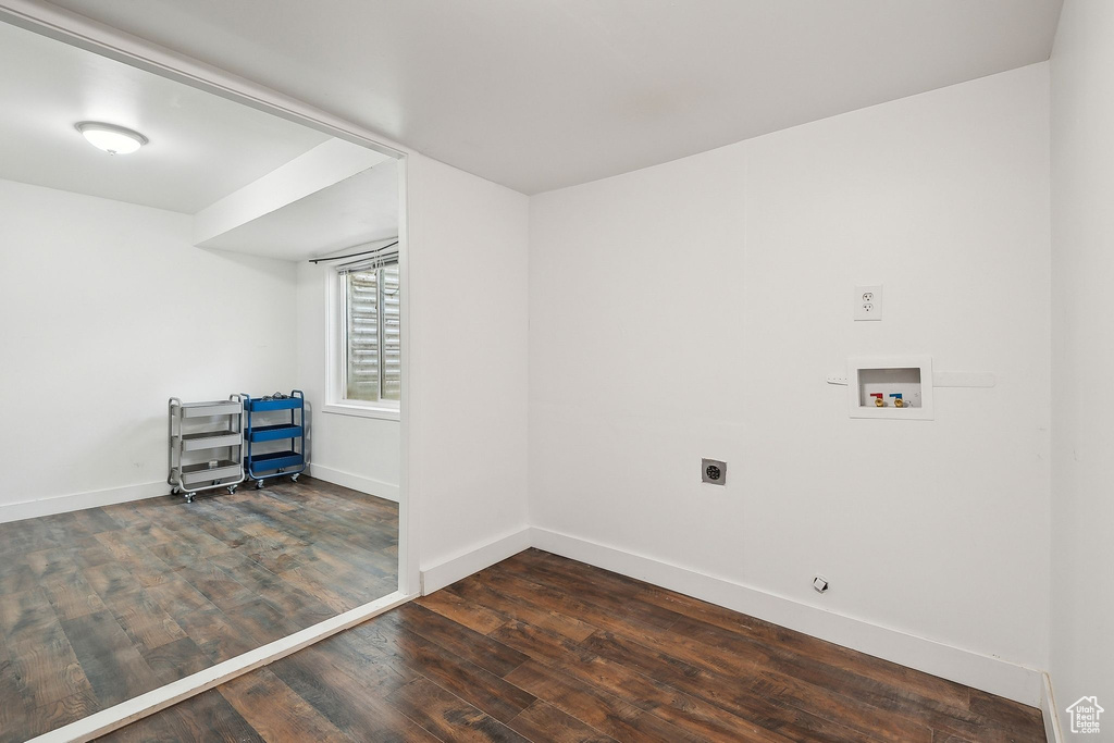 Washroom with electric dryer hookup, hookup for a washing machine, wood finished floors, and baseboards