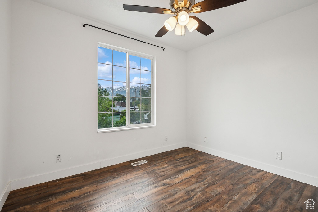 Unfurnished room with healthy amount of natural light, wood finished floors, baseboards, and ceiling fan