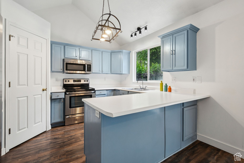 Kitchen featuring stainless steel appliances, a sink, a peninsula, vaulted ceiling, and blue cabinets