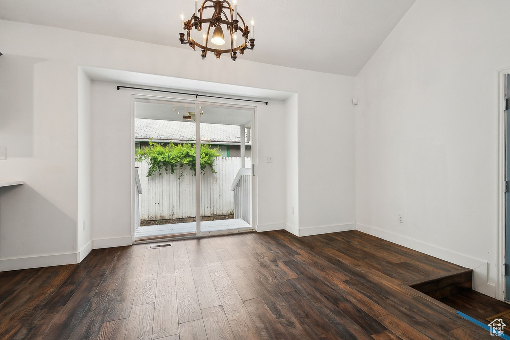 Unfurnished dining area featuring a chandelier, dark wood-style floors, and baseboards