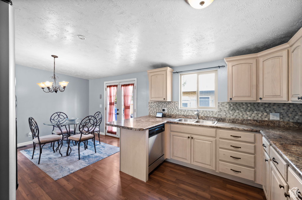 Kitchen featuring a sink, dishwasher, backsplash, a peninsula, and dark wood finished floors