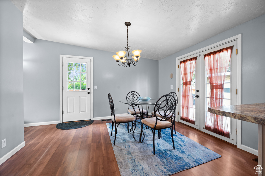 Dining room with wood finished floors, baseboards, a chandelier, and french doors