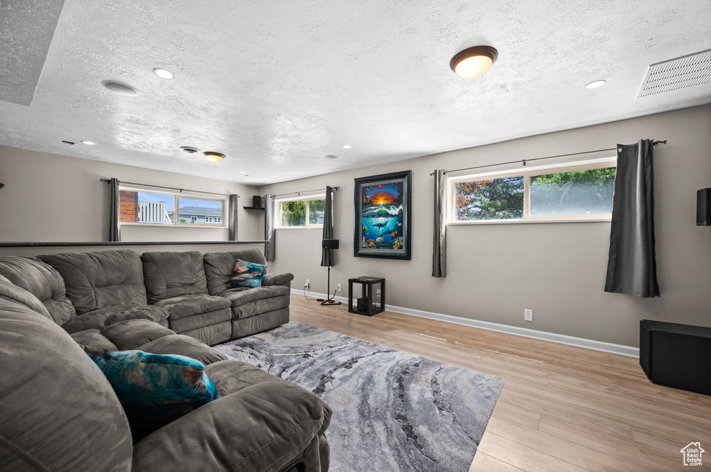 Living room featuring wood finished floors, a textured ceiling, baseboards, and recessed lighting