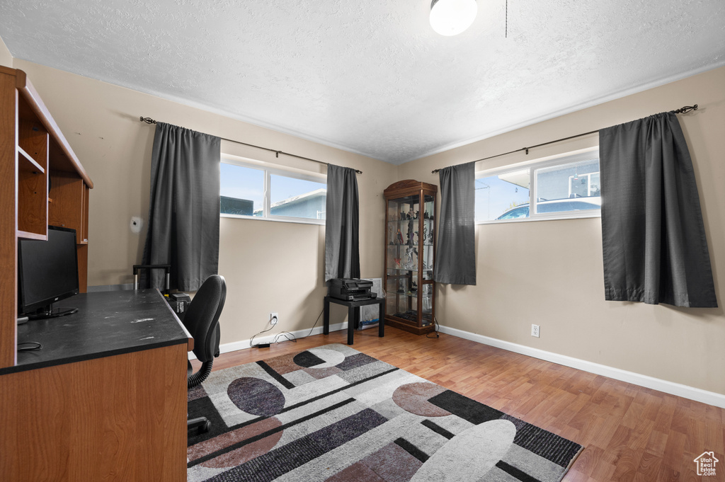 Office with a textured ceiling, wood finished floors, healthy amount of natural light, and baseboards