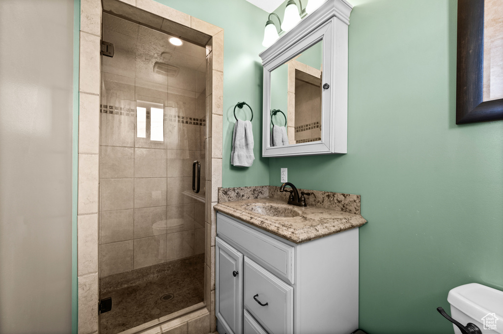Bathroom featuring toilet, a shower stall, and vanity