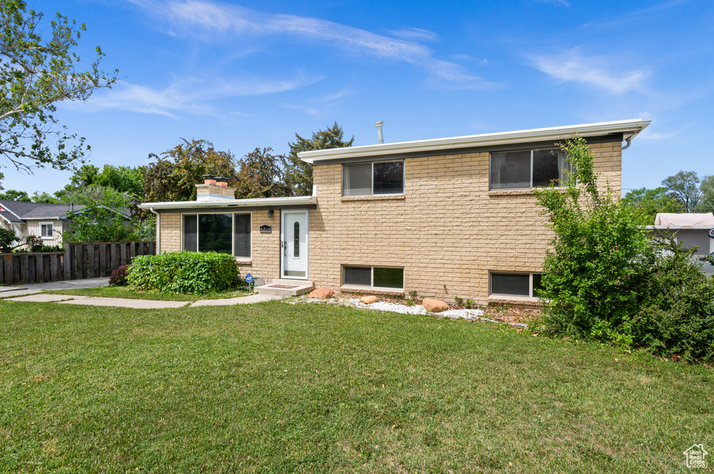 Split level home featuring a chimney and brick siding