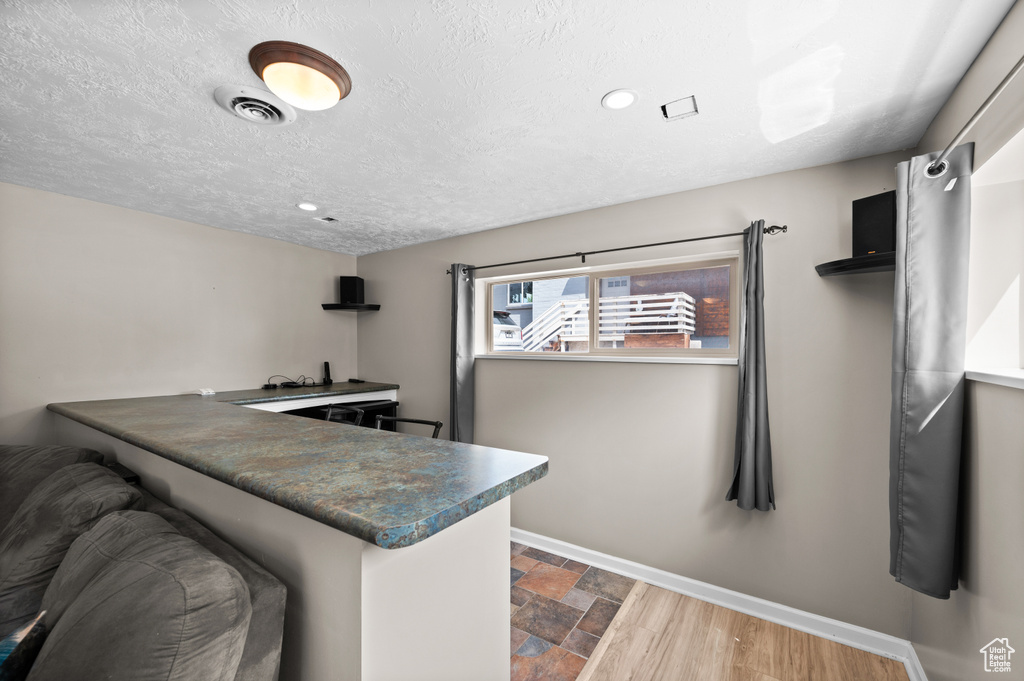 Kitchen featuring baseboards, dark countertops, dark stone finish floors, recessed lighting, and a peninsula