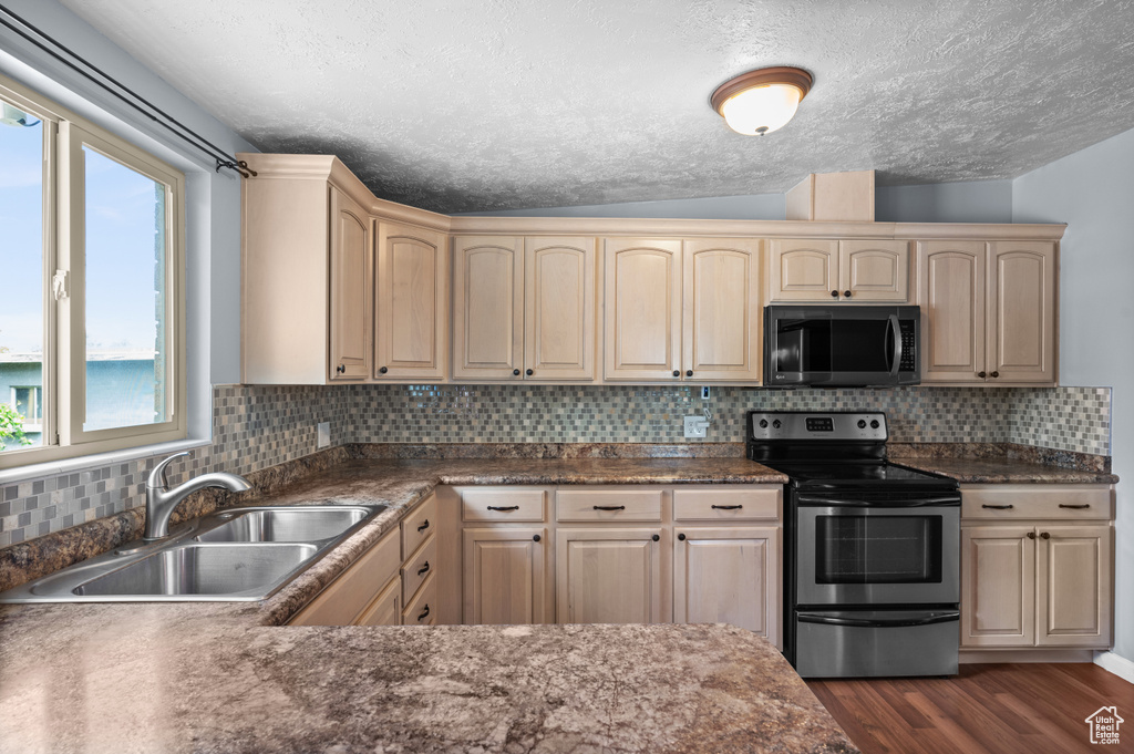 Kitchen with stainless steel electric stove, a sink, a textured ceiling, dark wood finished floors, and light brown cabinets