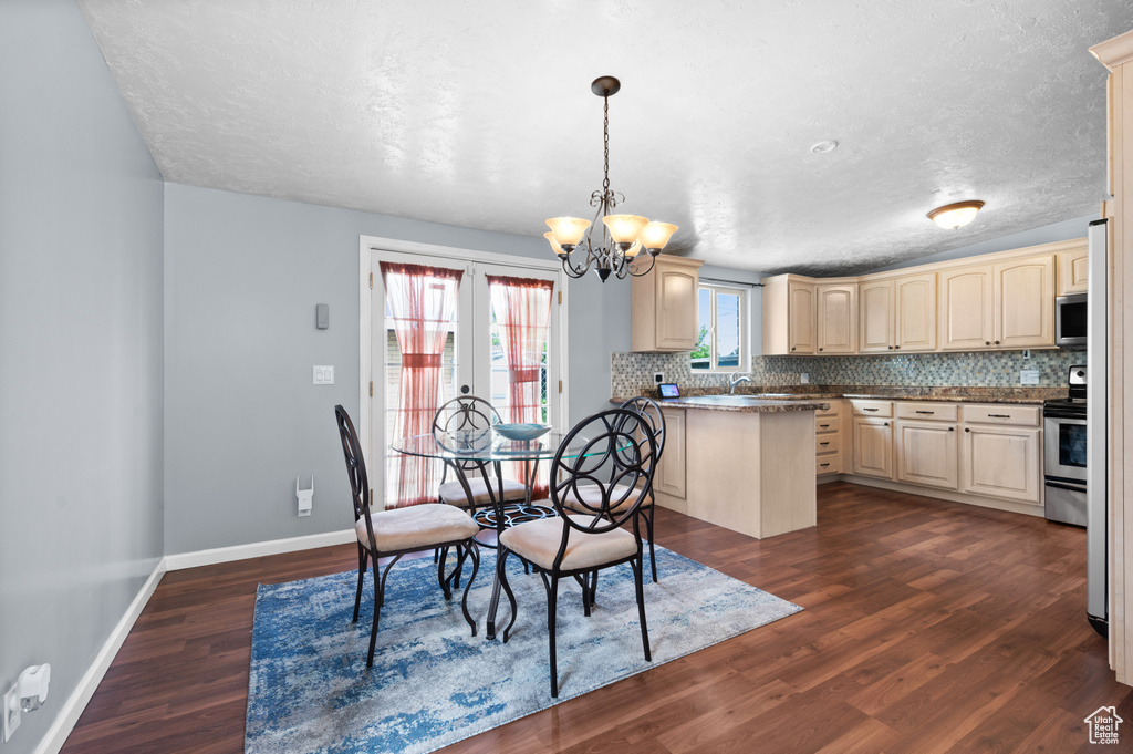 Dining space featuring a chandelier, baseboards, dark wood finished floors, and a textured ceiling