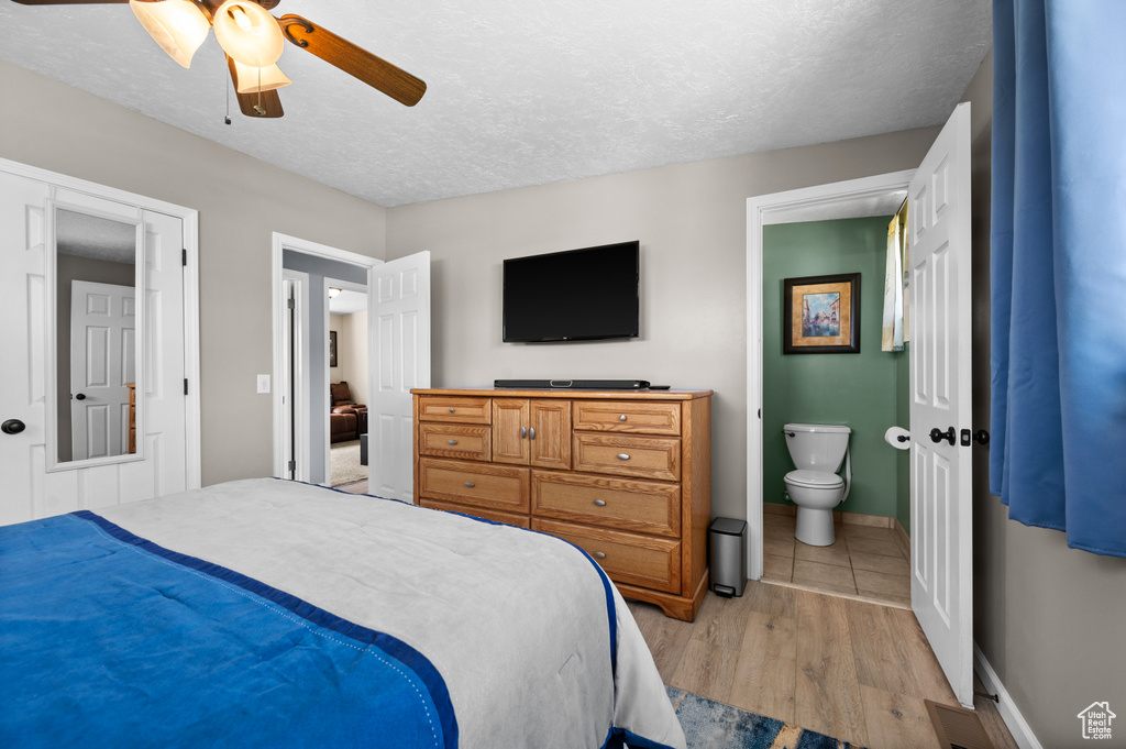 Bedroom with light wood finished floors, a textured ceiling, connected bathroom, ceiling fan, and baseboards