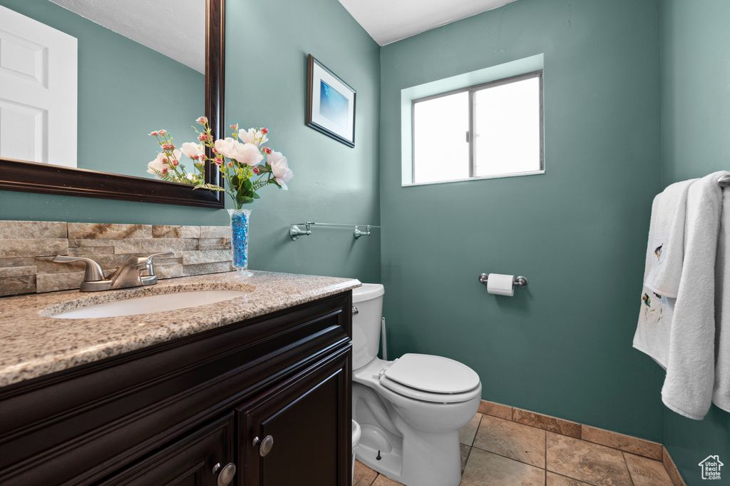 Half bath featuring toilet, vanity, and baseboards