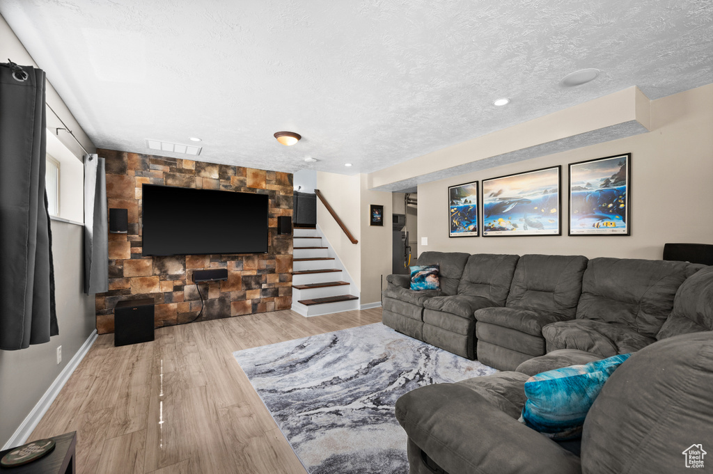 Living area with stairs, wood finished floors, baseboards, a textured ceiling, and recessed lighting
