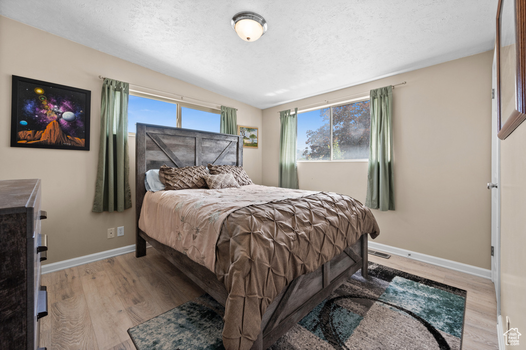 Bedroom featuring a textured ceiling, baseboards, and light wood-type flooring
