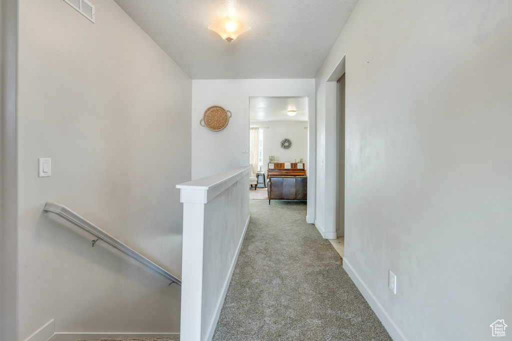 Corridor with an upstairs landing, light carpet, and baseboards