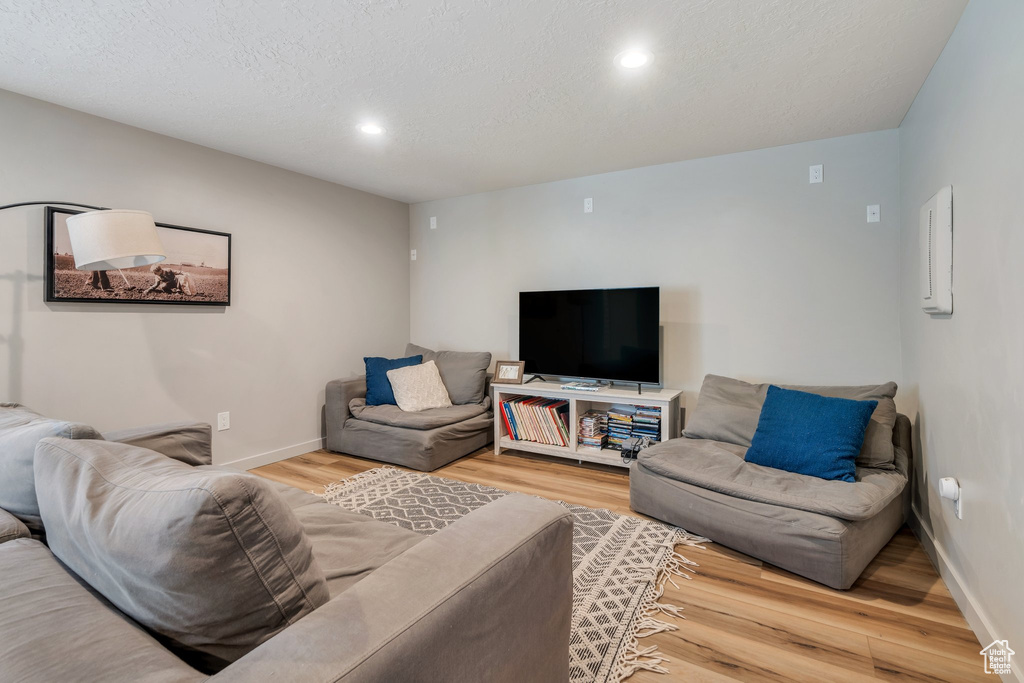 Living area with wood finished floors, recessed lighting, baseboards, and a textured ceiling