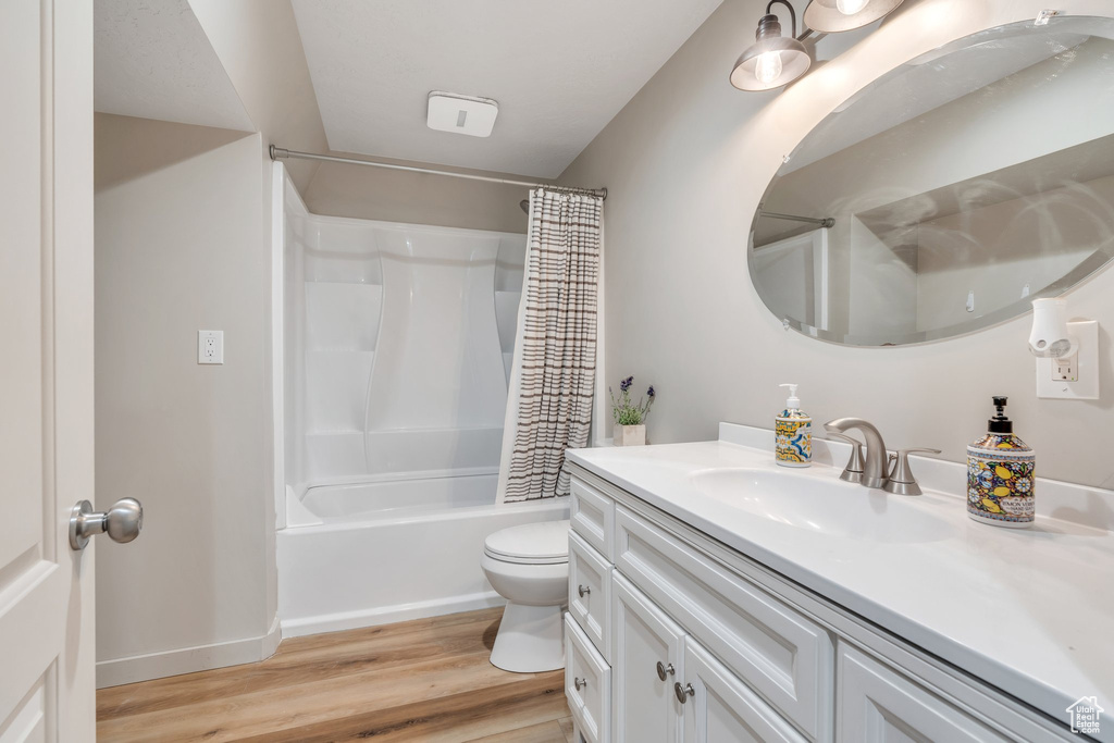 Full bathroom featuring wood finished floors, vanity, toilet, shower / tub combo, and baseboards