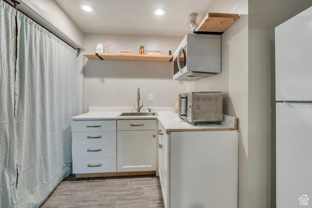 Laundry room with a sink, recessed lighting, and light wood finished floors