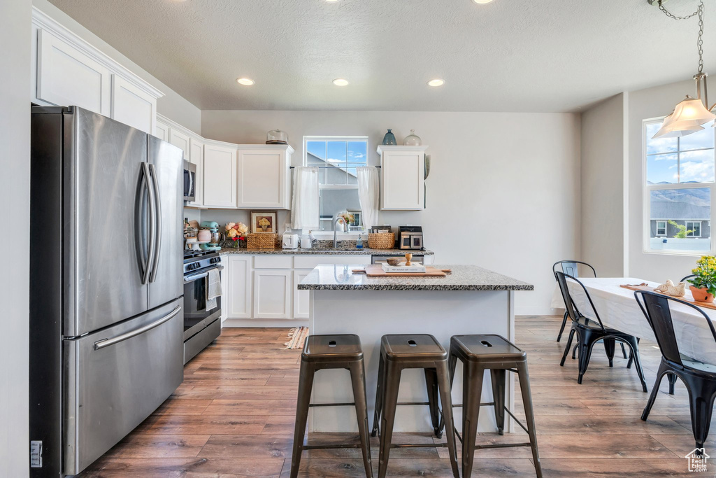 Kitchen with appliances with stainless steel finishes, white cabinets, healthy amount of natural light, recessed lighting, and a textured ceiling