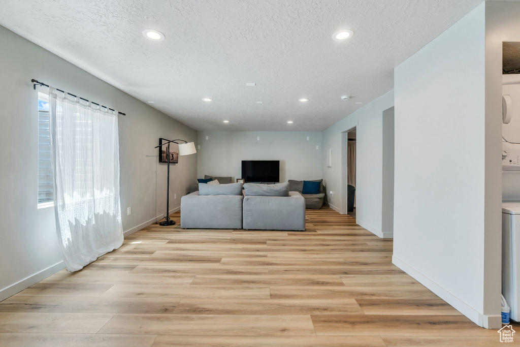 Living room with recessed lighting, a textured ceiling, light wood-style flooring, and baseboards