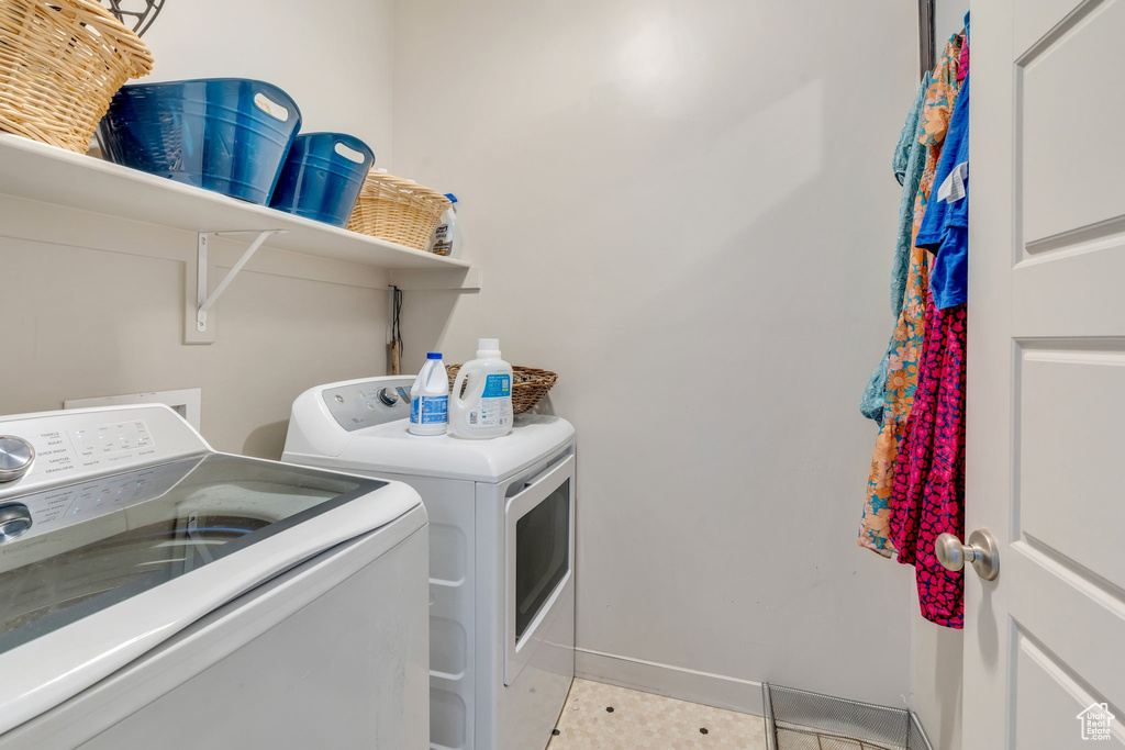 Laundry area featuring independent washer and dryer, light tile patterned flooring, and baseboards
