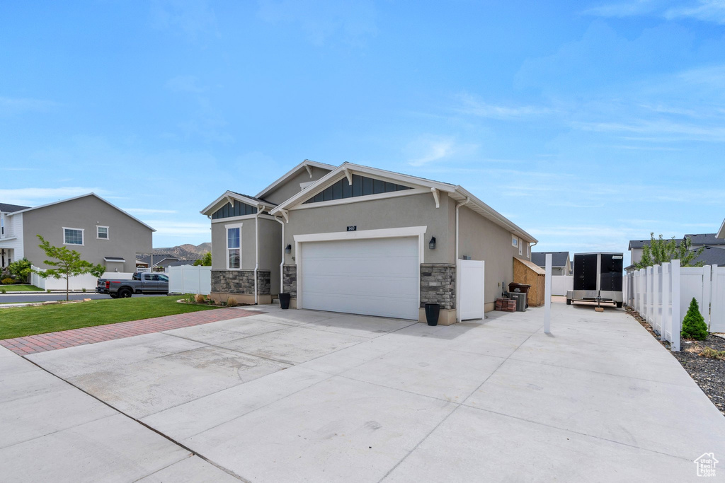 View of front of property featuring driveway, stone siding, stucco siding, and a garage