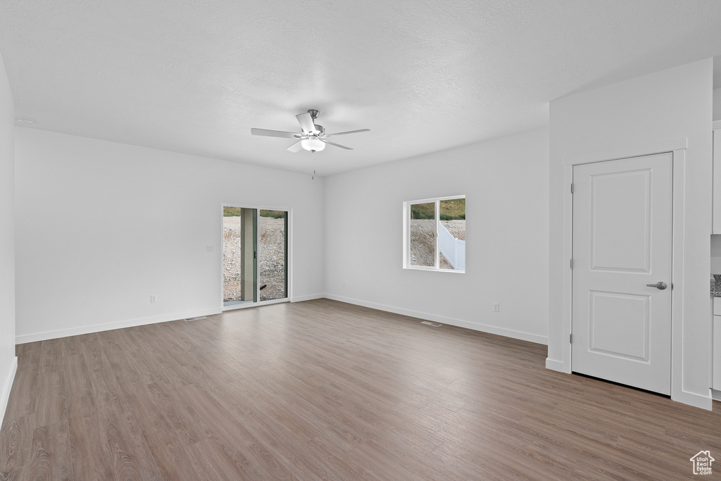 Spare room with plenty of natural light, a ceiling fan, and wood finished floors