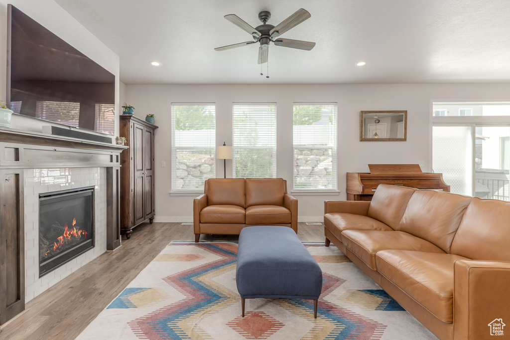 Living room with a fireplace, a ceiling fan, light wood-style flooring, recessed lighting, and baseboards