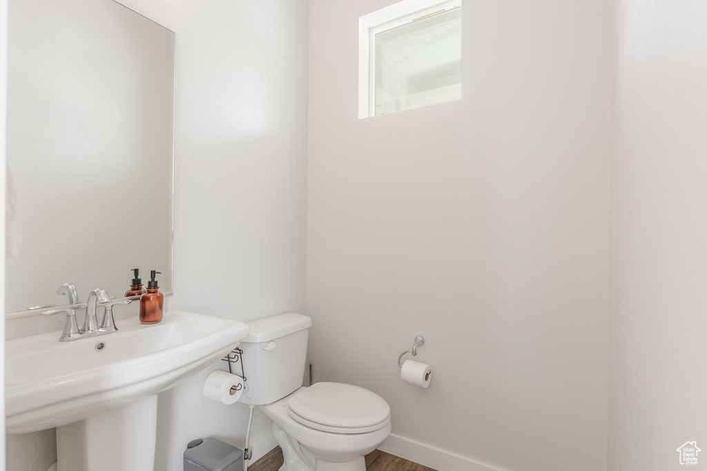 Half bath with toilet, a sink, and baseboards