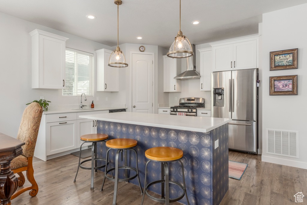 Kitchen featuring appliances with stainless steel finishes, a sink, wood finished floors, light countertops, and recessed lighting