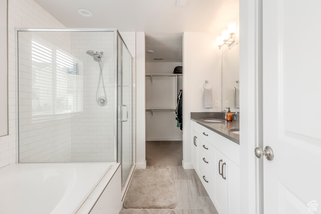 Bathroom with a shower stall, a garden tub, double vanity, and a spacious closet