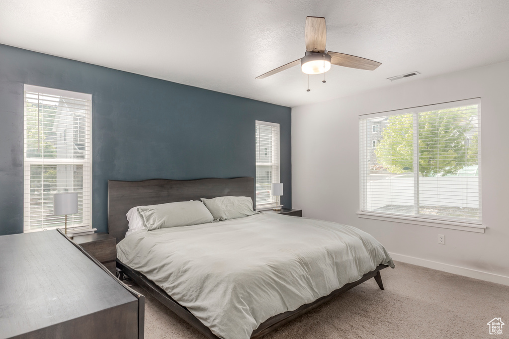 Bedroom featuring multiple windows, carpet flooring, baseboards, and ceiling fan