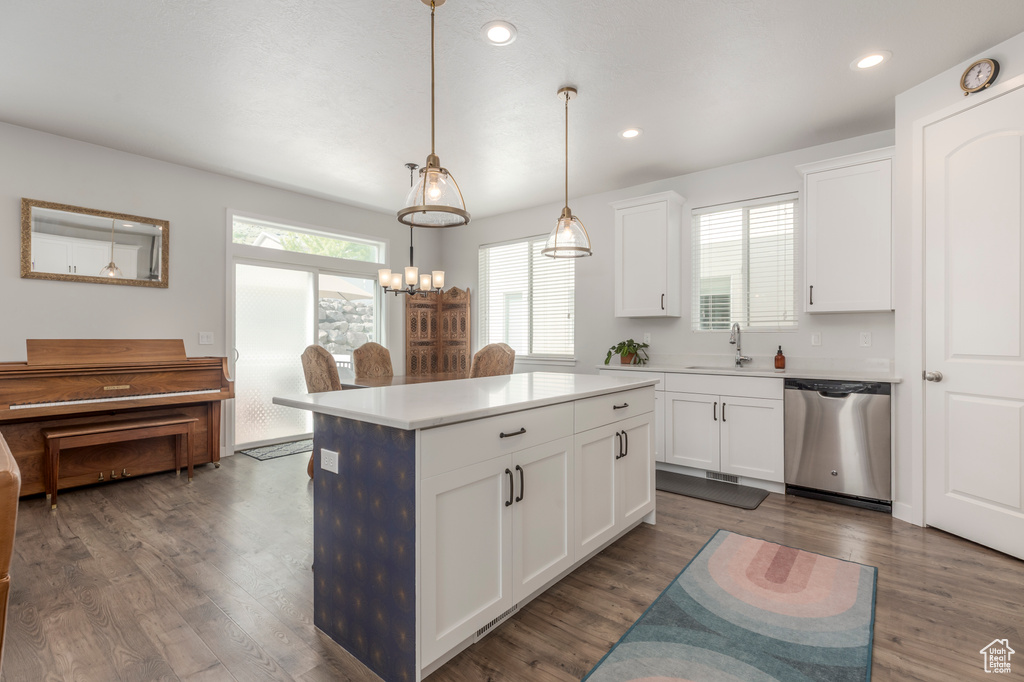 Kitchen featuring stainless steel dishwasher, a sink, a kitchen island, white cabinets, and light countertops