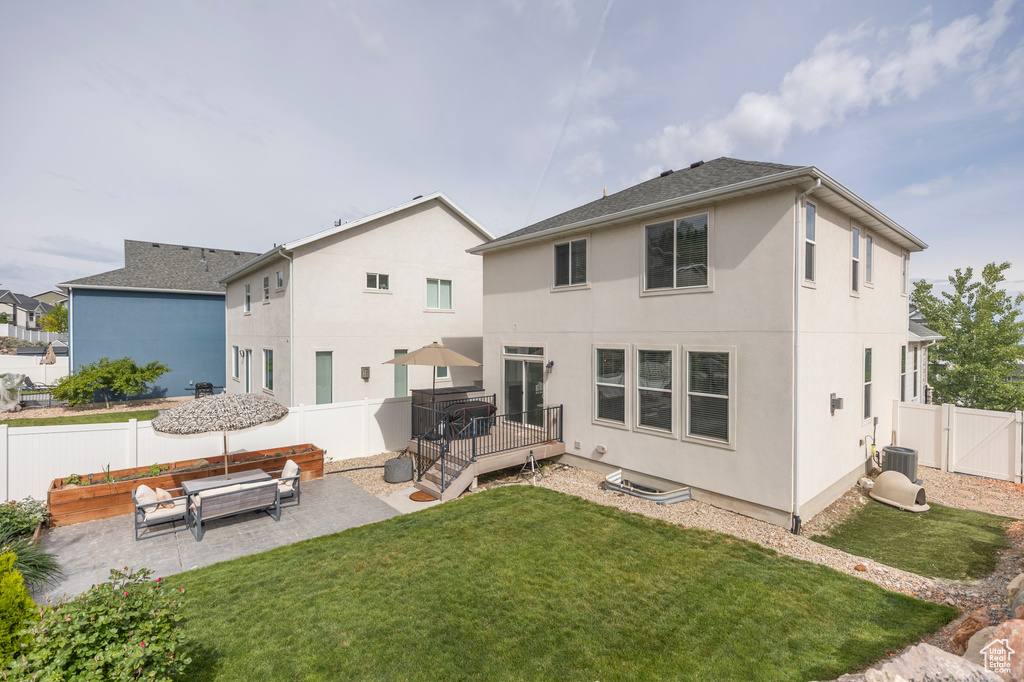 Back of property featuring stucco siding, a patio, a deck, and central AC unit