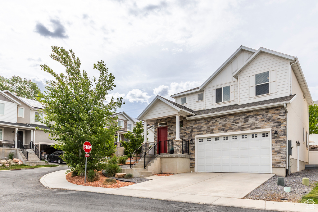 View of front of house featuring a garage, driveway, stone siding, and board and batten siding