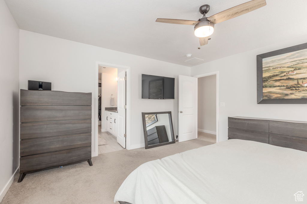 Bedroom with light colored carpet, baseboards, connected bathroom, and ceiling fan