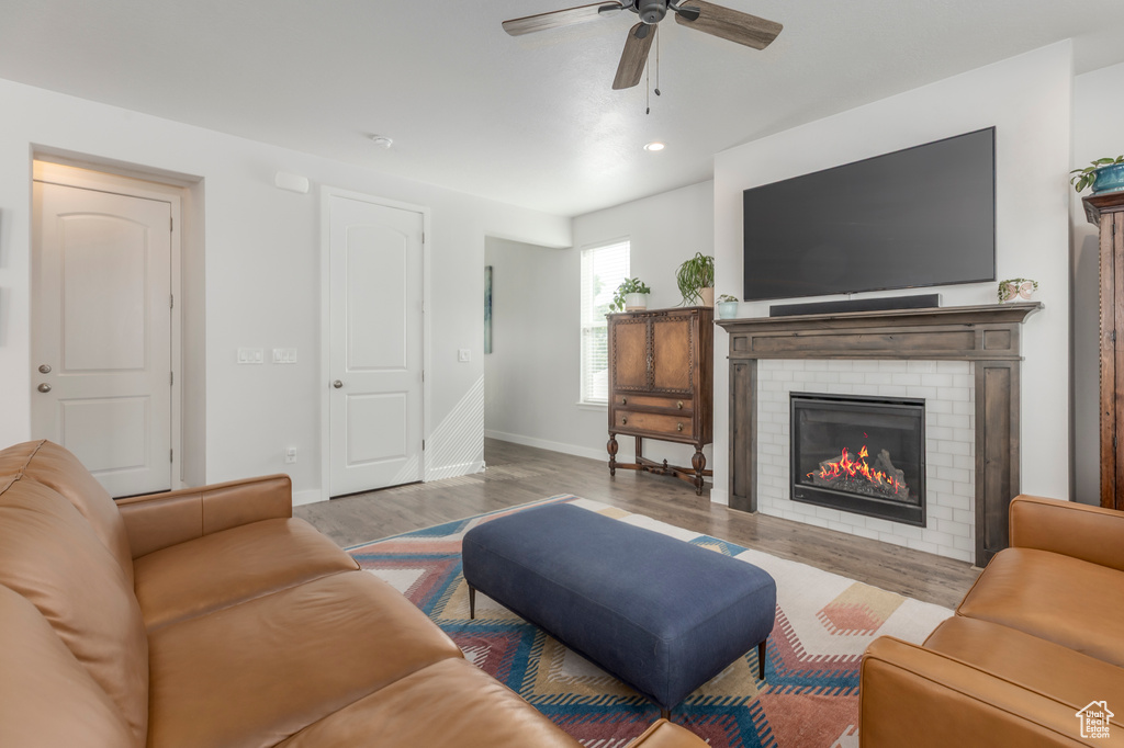 Living room with baseboards, ceiling fan, wood finished floors, a brick fireplace, and recessed lighting