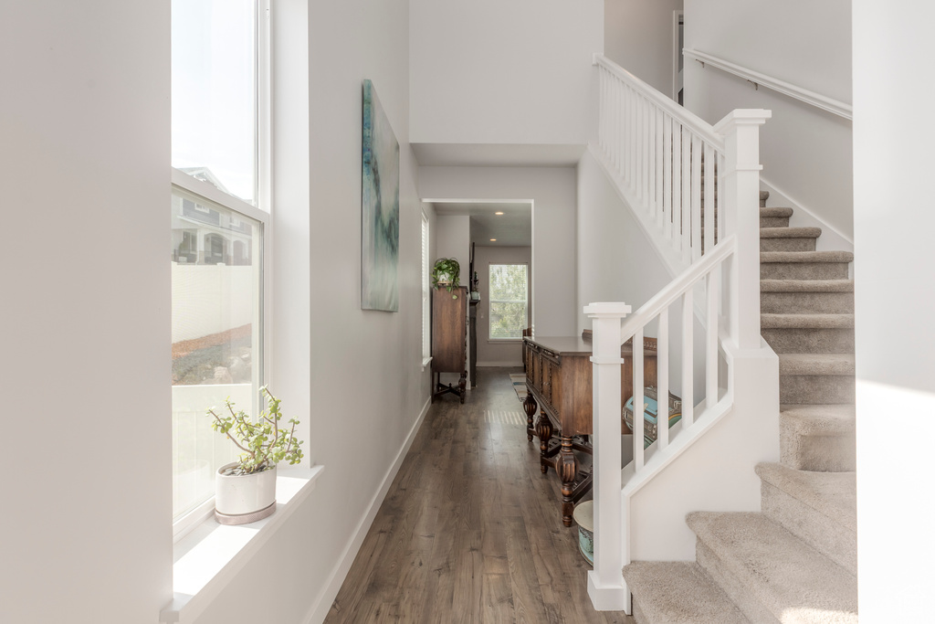 Entrance foyer with wood finished floors, a towering ceiling, stairs, and baseboards