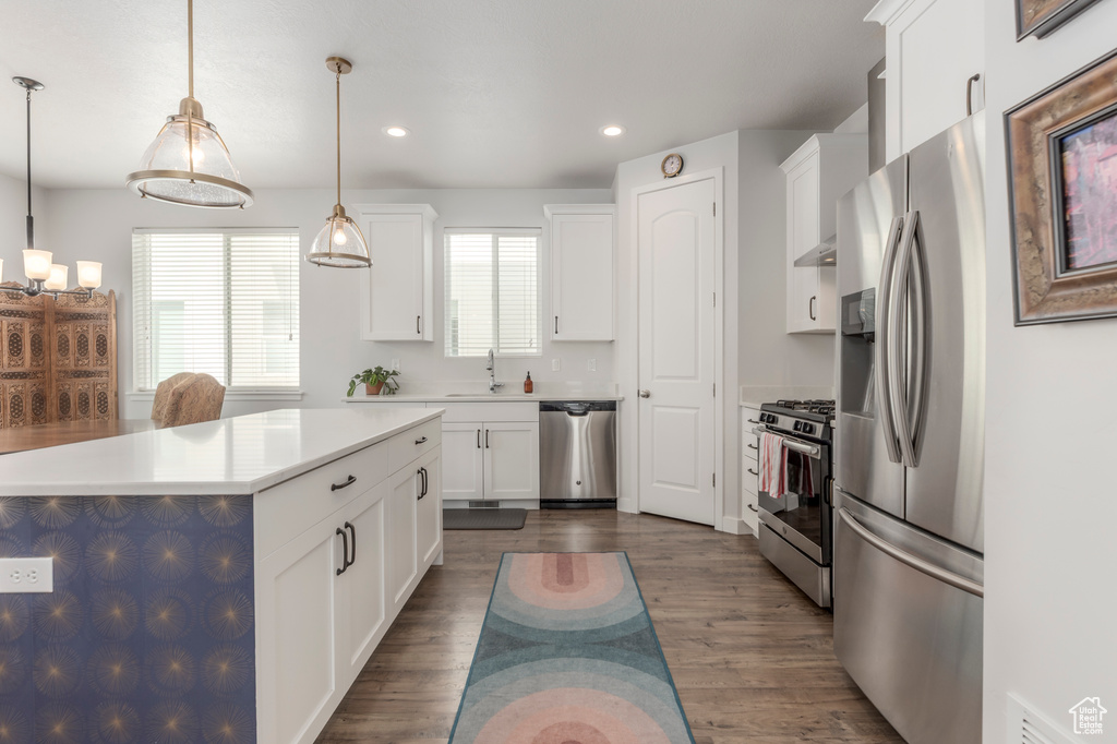 Kitchen featuring appliances with stainless steel finishes, recessed lighting, white cabinets, decorative light fixtures, and a sink