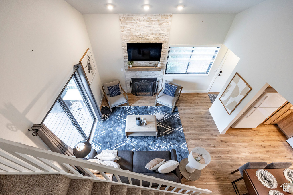 Living room with wood finished floors, a stone fireplace, and baseboards