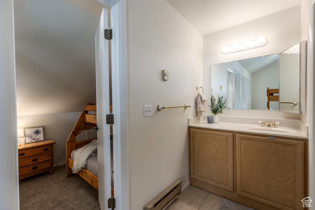 Bathroom featuring baseboard heating, lofted ceiling, and vanity