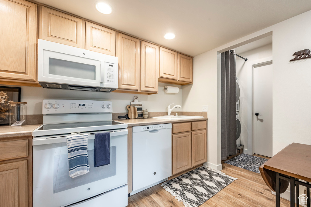Kitchen with white appliances, light brown cabinets, a sink, light wood finished floors, and light countertops